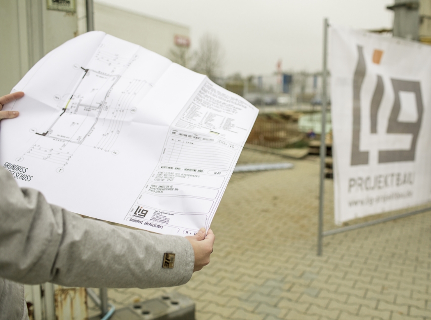 Leistungen bei der LIG. Bild zeigt Person mit einem Grundrissplan in der Hand.