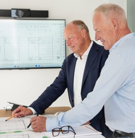 Bild zeigt eine Besprechungssituation mit Bauplan.